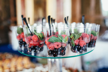 Cups with berries and mint on white dish