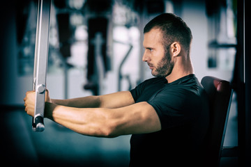 Fototapeta na wymiar muscular man working on fitness machine at the gym