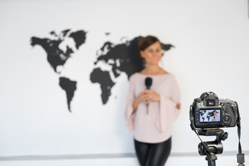 Journalist reporting from the studio on the background of the world map in front of the camera....