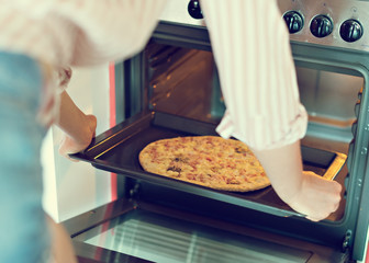 Woman preparing pizza bought in a store.