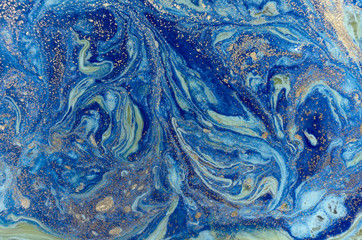 Marbled green and blue abstract background with golden sequins. Liquid marble ink pattern.