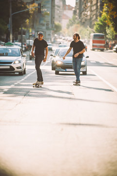 Two pro skateboard rider ride skate through cars on street
