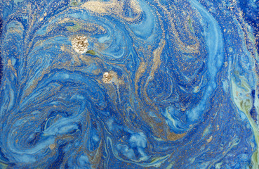 Marbled blue abstract background with golden sequins. Liquid marble ink pattern.