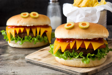 Halloween burger monsters with french fries on wooden table
