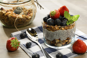 Yogurt with granola, fresh blueberries, chia seeds and oats in a glass over wood background. close up