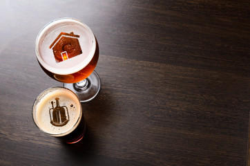 Local craft beer. House and heart silhouettes in two glasses of fresh beer on pub table, view from...