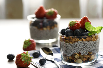 Yogurt with granola, fresh blueberries, chia seeds and oats in a glass over wood background. close up