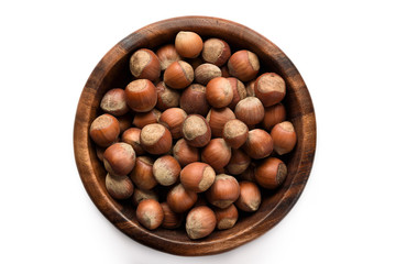 Hazelnuts in a wood bowl and loose isolated over white background.