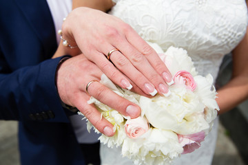 Obraz na płótnie Canvas Bride and groom hands with wedding rings and bridal bouquet