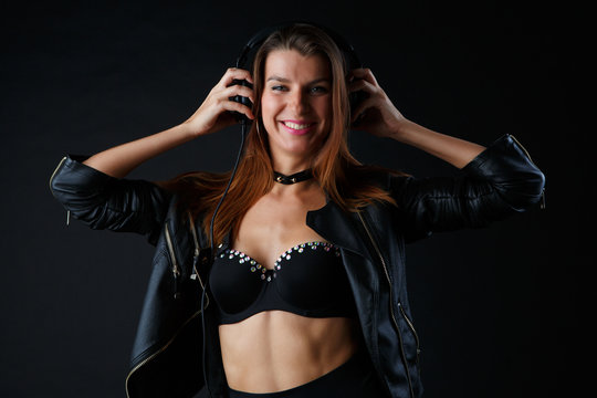 Image of young brunette wearing headphones in leather jacket
