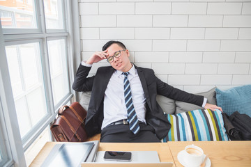 Portrait of an upset businessman at desk in coffee shop. Asian businessman being depressed by working in office.