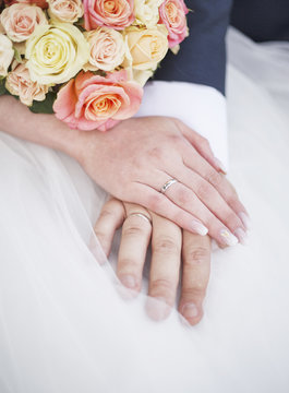 Bride and groom hands with wedding rings.