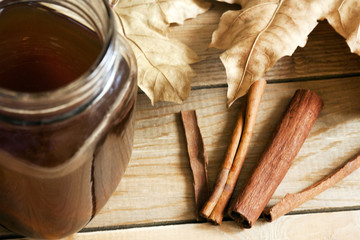 Autumn still life: fruit compote, dry maple leaves and cinnamon sticks on a wooden table