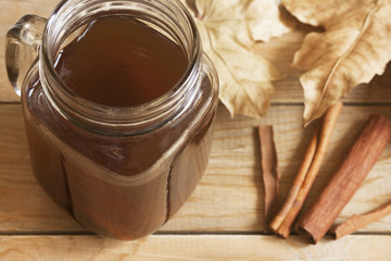 Autumn still life: fruit compote, dry maple leaves and cinnamon sticks on a wooden table