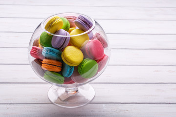 large glass vase full colorful macaroons. Place for the text