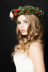 Christmas Woman Fashion Model wearing Christmas Wreath with Red Glass Balls, Xmas Tree Twig and Berry on Black Background