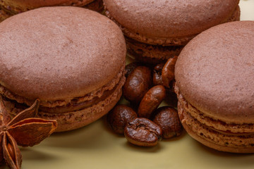 chocolate Macaroons and Dark Roasted Coffee Beans on yellow Background. Selective Focus