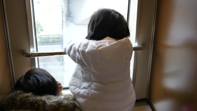 Happy asian children looking out train window outside 