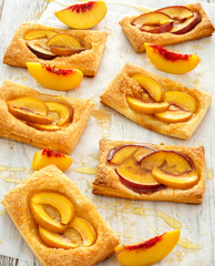Tasty fresh homemade puff pastry with peach and honey on the white wooden table
