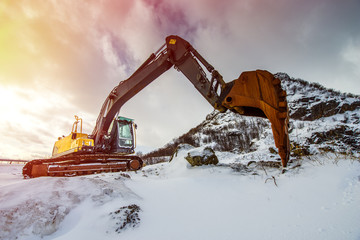 Large yellow excavator on the background of a winter landscape - obrazy, fototapety, plakaty