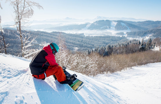 Shot of a male snowboarder in winter sportswear helmet and skiing mask sitting on the slope preparing for riding copyspace active lifestyle winter sports recreation ski resort Bukovel