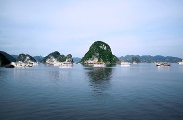 View of green islands in Halong Bay at day from a distance with white boats on the water, UNESCO World Heritage Site, Vietnam, Southeast Asia.