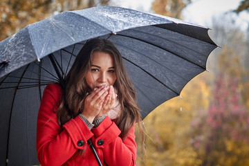 The girl under the umbrella warms her hands with her breath