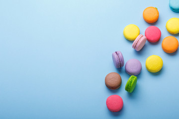 A photo of colorful macarons, shot from above on a blue background. place for text