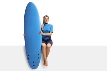 Female surfer with a surfboard sitting on a panel