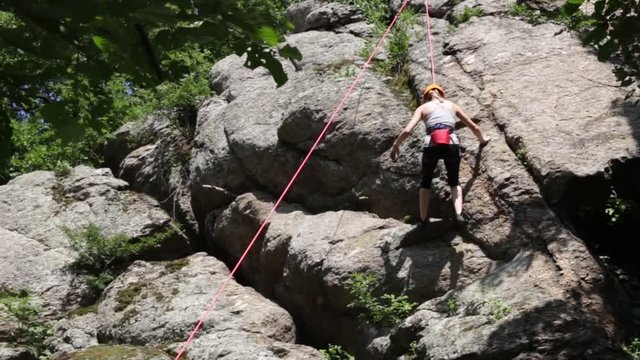 Girl rappelling down a hill