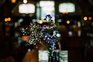 Flowers in hip beer bottle vase in restaurant or cafe