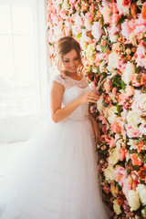 beautiful bride on the background of a wall of flowers