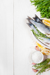 White wooden background with fresh raw fish and ingredients