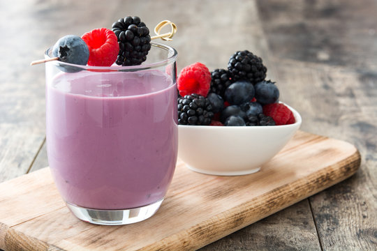 Healthy berry smoothie in glass on wooden table