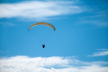 Paraglider flying in the blue sky against the background of clouds. Paragliding in the sky on a sunny day.