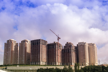 Fototapeta na wymiar Building crane and buildings under construction against noon sky