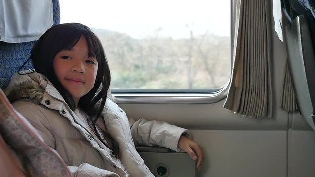 Little asian girl looking through window. She travels on a train slow motion 