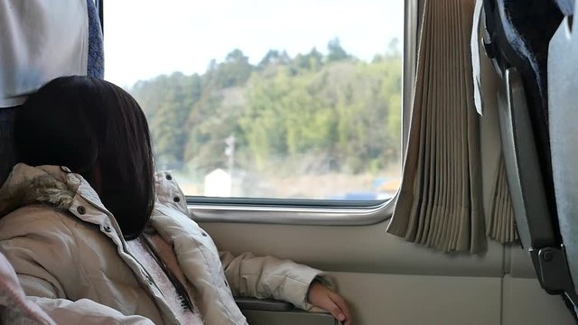 Little asian girl looking through window. She travels on a train slow motion 