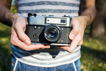 Young man holding in hands old vintage camera. Man photographer and film retro camera. Say cheese! 
