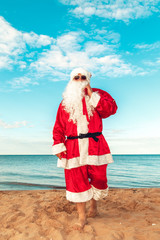 Obraz premium Santa Claus with a bag of gifts on the beach. The symbol of Christmas.