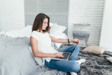 Beautiful young woman working from home on a laptop sitting on the floor in the room