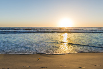 California. South of the USA.  Footprints on the sand of the beach. Sunset bright sun sets over the horizon. Beautiful beaches of California. South of the USA