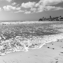 Clouds in California blue sky. Ocean surf. Sea white foam on sand beach. California coast near San...