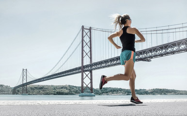 Blonde woman running training on the coastline near the Bridge u