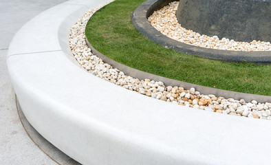 White curve stone bench decorated with white gravel and lawn. for public space.
