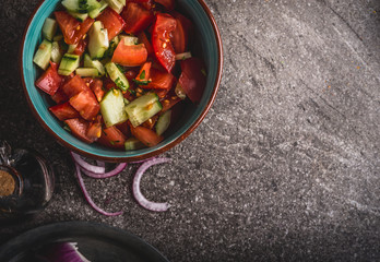 Healthy tomatoes cucumber salad served on gray stone background, top view, close up. Healthy, diet  and clean food and eating  concept.