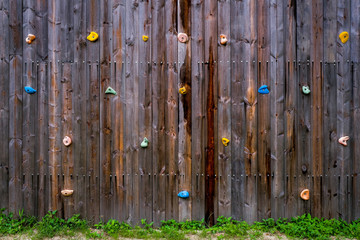 hand and footholds on a wooden outdoor climbing wall in a close up full frame view for a recreational challenge or for practising for the extreme sport of rock climbing