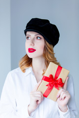 Young redhead woman in hat holding christmas gift box