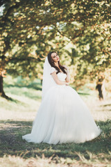 Obraz na płótnie Canvas Beautiful bride posing in wedding dress outdoors