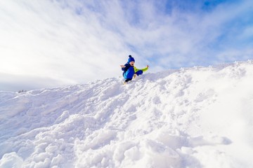 Naklejka na ściany i meble Child having fun at snowy hill.